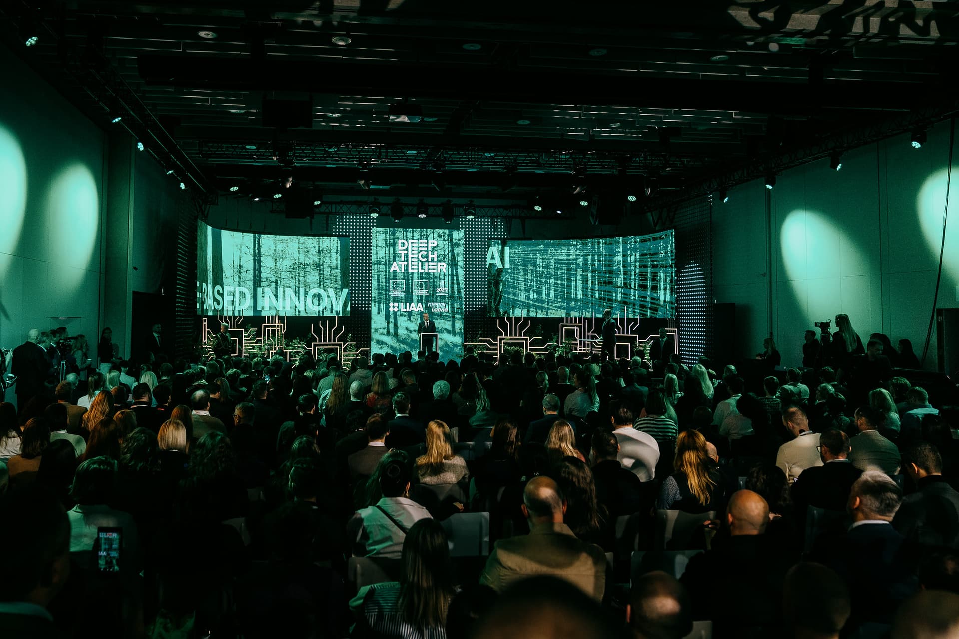 Deep tech Eiropā sola līdz pat miljonam jaunu darbavietu - kā inovāciju attīstību paātrinājis karš Ukrainā? Deep Tech Atelier 2025 skatuve, kur priekšplānā redzama auditorija.