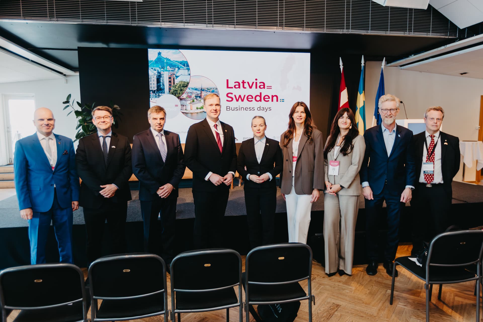 Latvijas uzņēmēji Zviedrijā veido jaunus sadarbības projektus tehnoloģiju, aizsardzības un zaļās transformācijas jomās Oficiālās vizītes dalībnieku kopbilde, kur fonā redzama prezentācija "Latvia Sweden"
